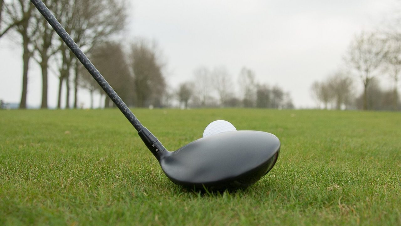 Golf driver set behind a teed-up ball