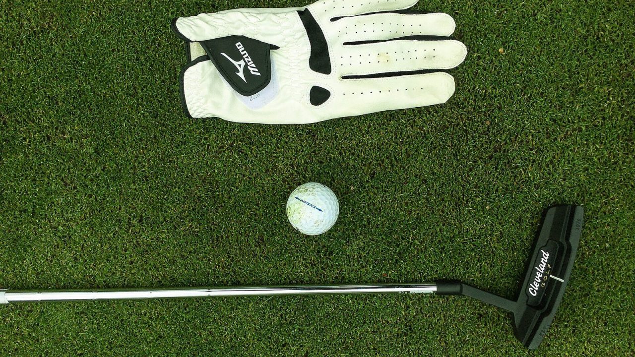 Several golf balls lying next to a golf glove