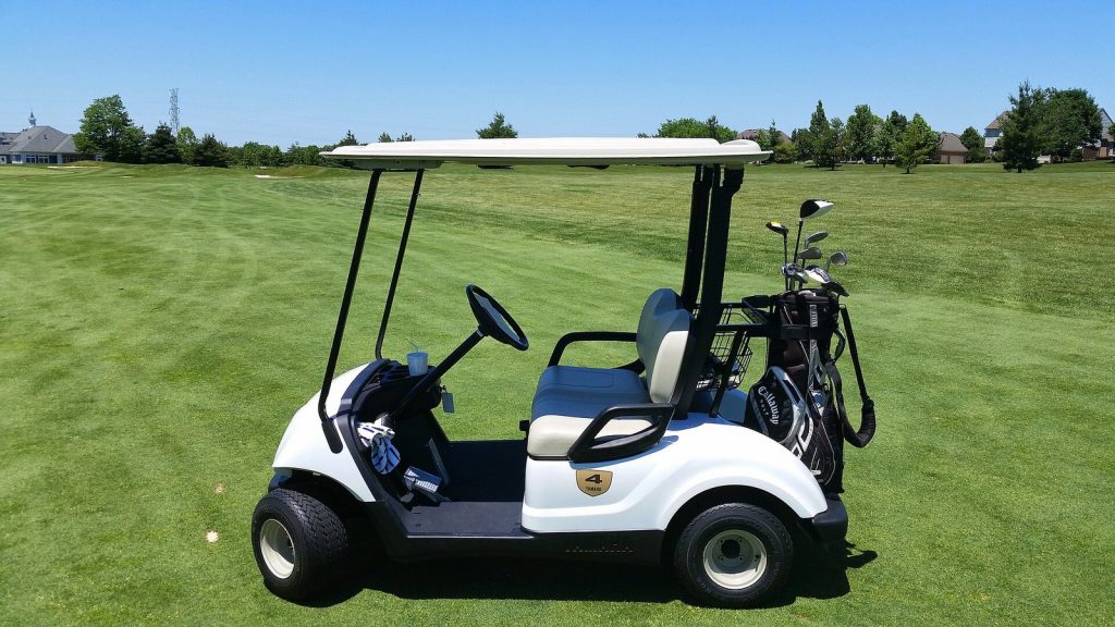 Golf cart parked on the edge of a fairway